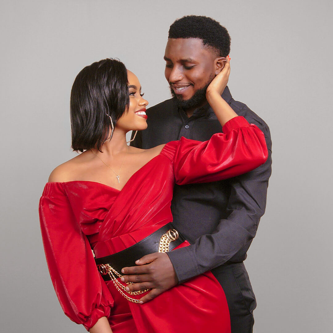 Woman in red dress and man in black button down posing for Valentine's Day photos