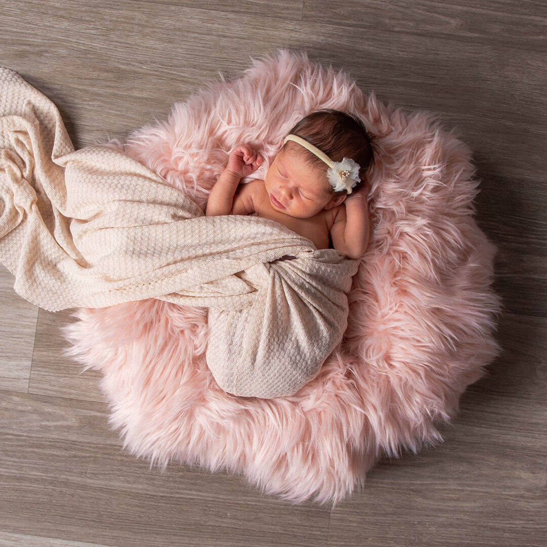 Newborn baby in cloth wrap on a during a JCPenney Portrait Studios photoshoot.