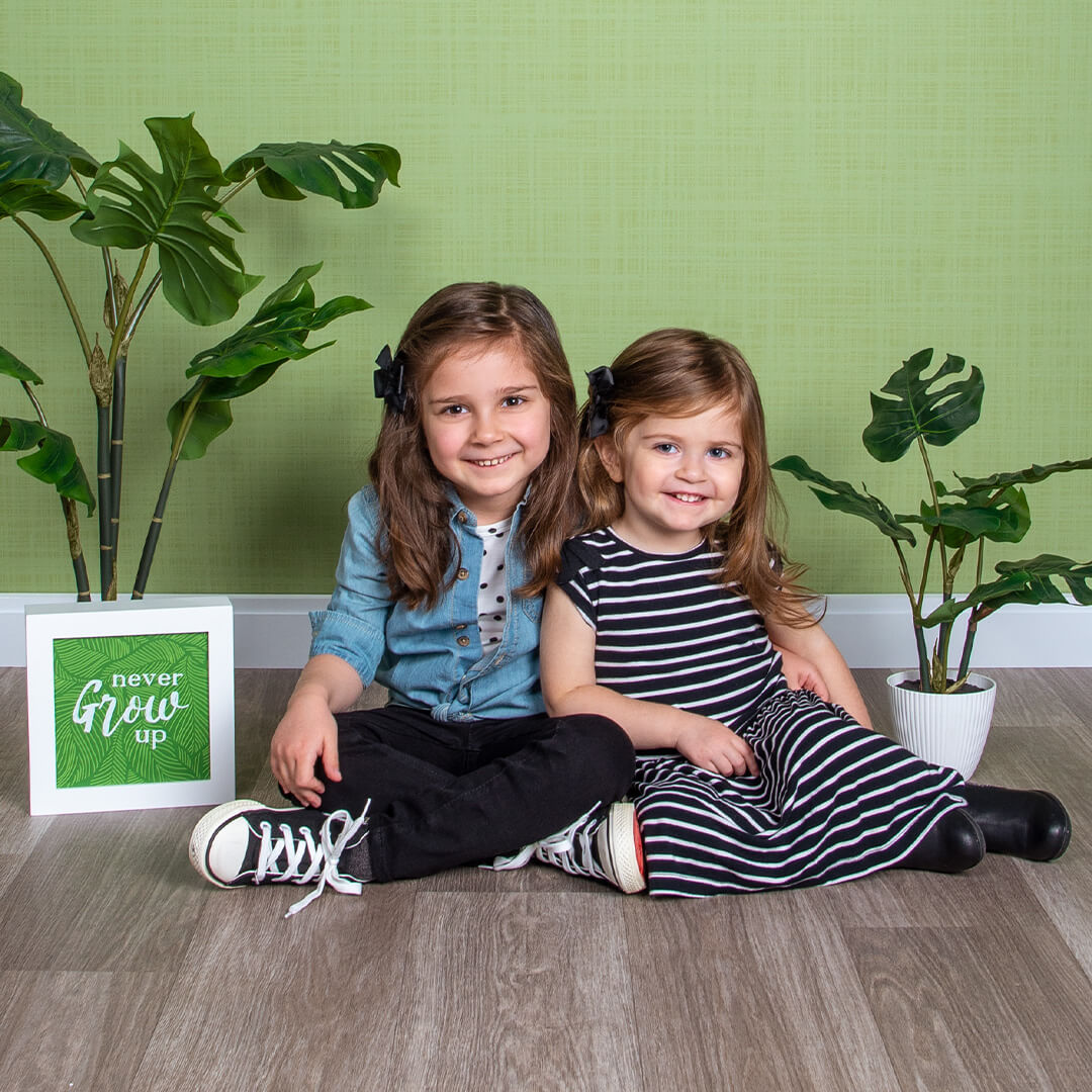 Sisters sitting on the floor with props and posing for photos