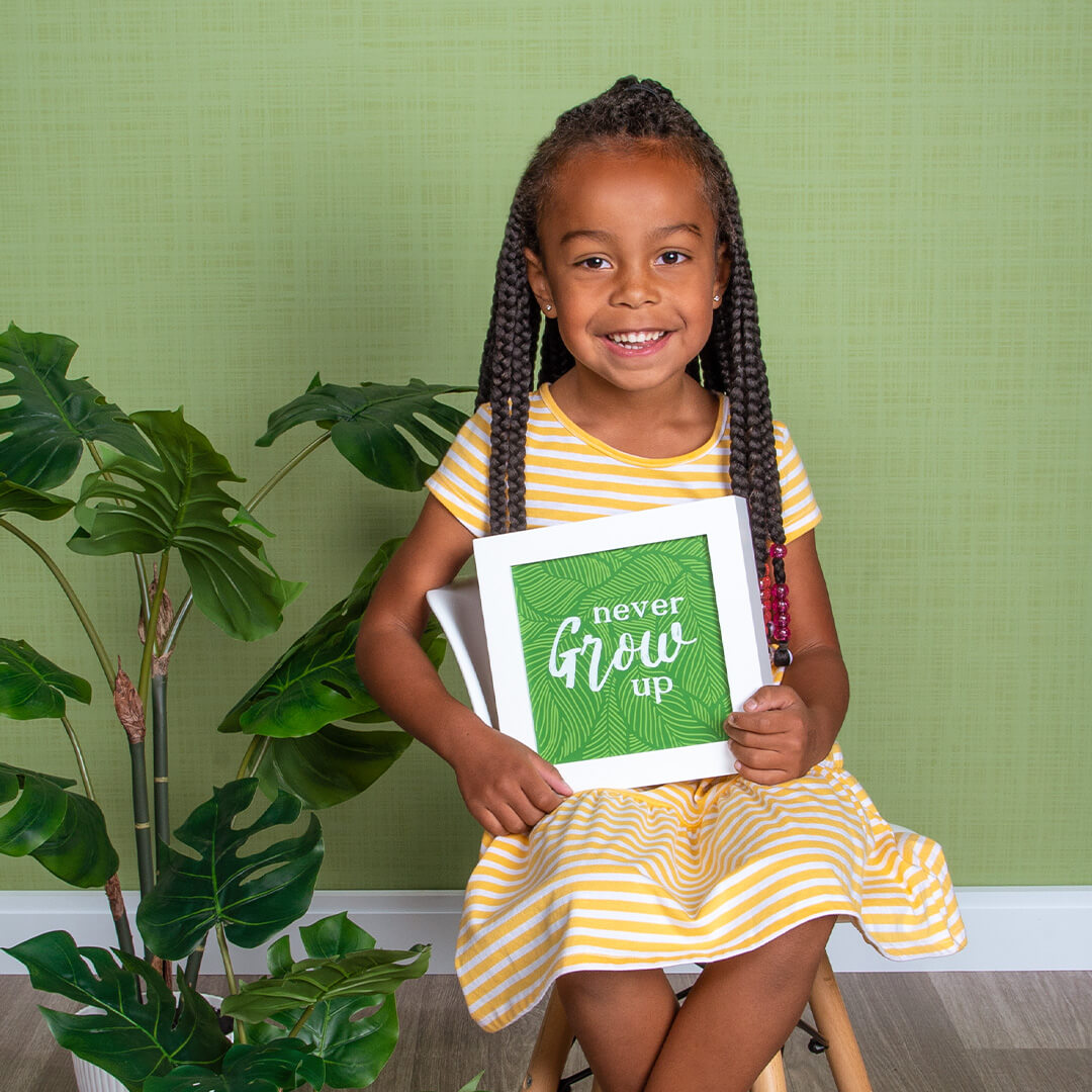 Girl holding a prop for JCPenney Portraits photos on a green background