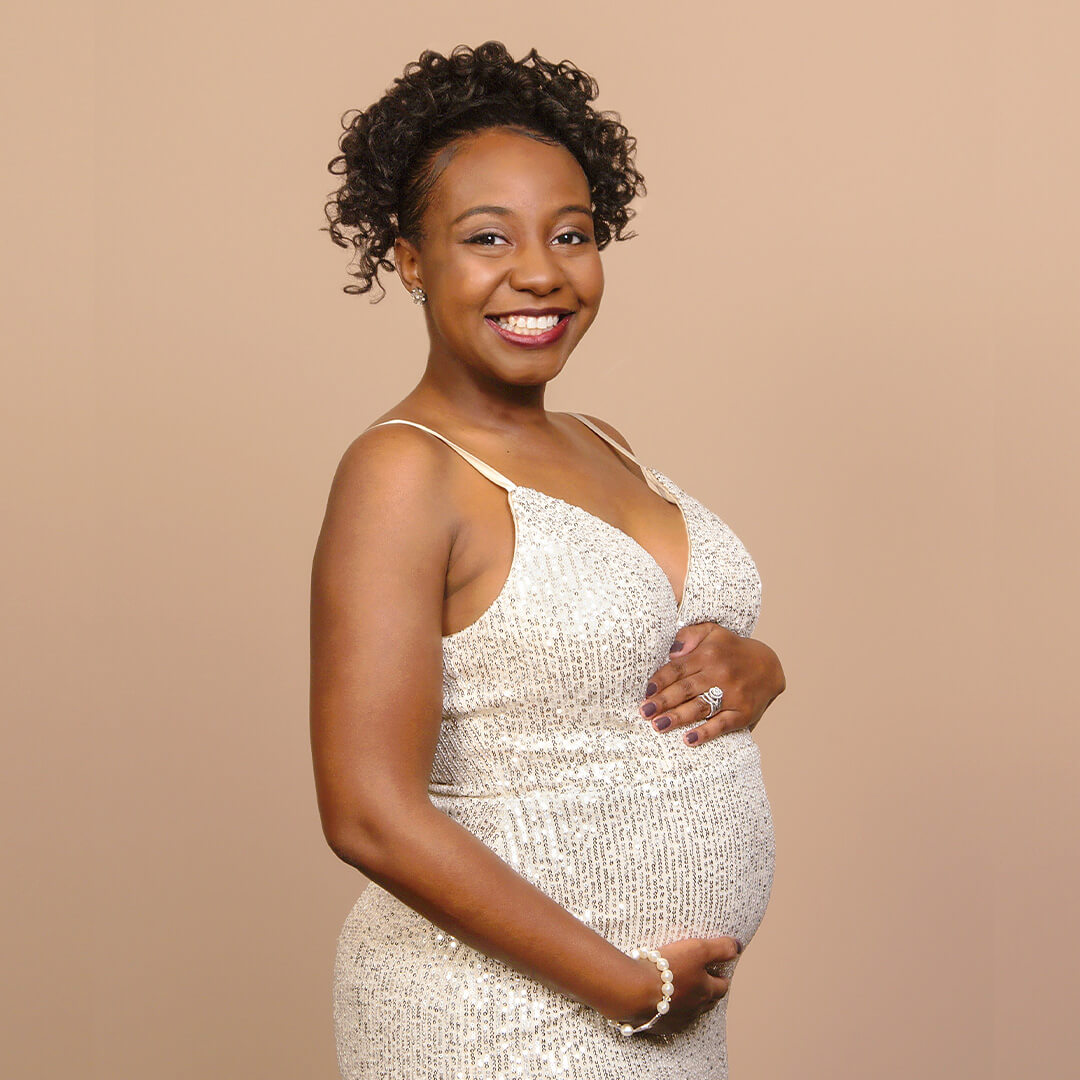 Woman in sparkly white dress holding her belly for maternity pictures