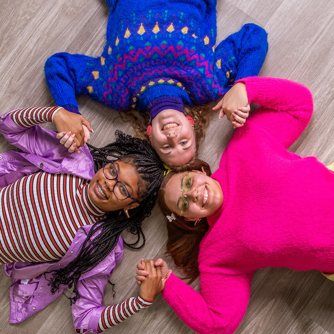 Three women on the floor holding hands for retro photography