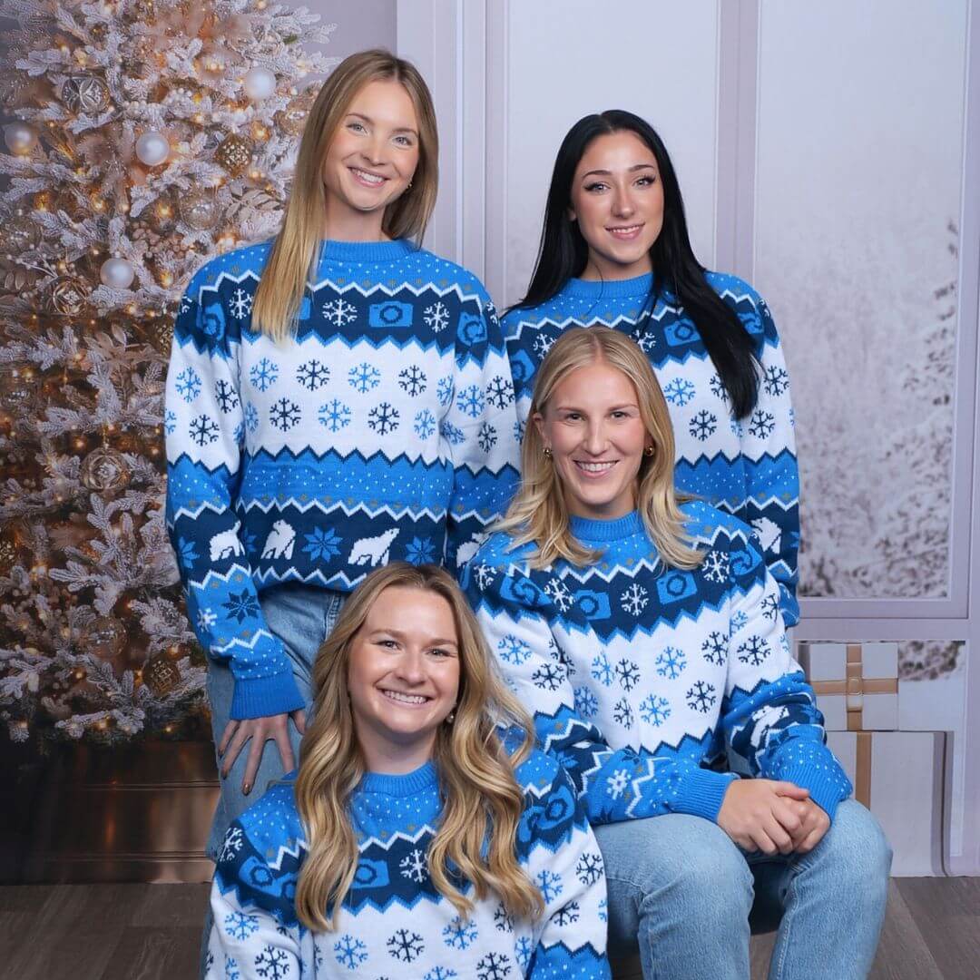 Women in holiday sweaters posing for festive holiday photos
