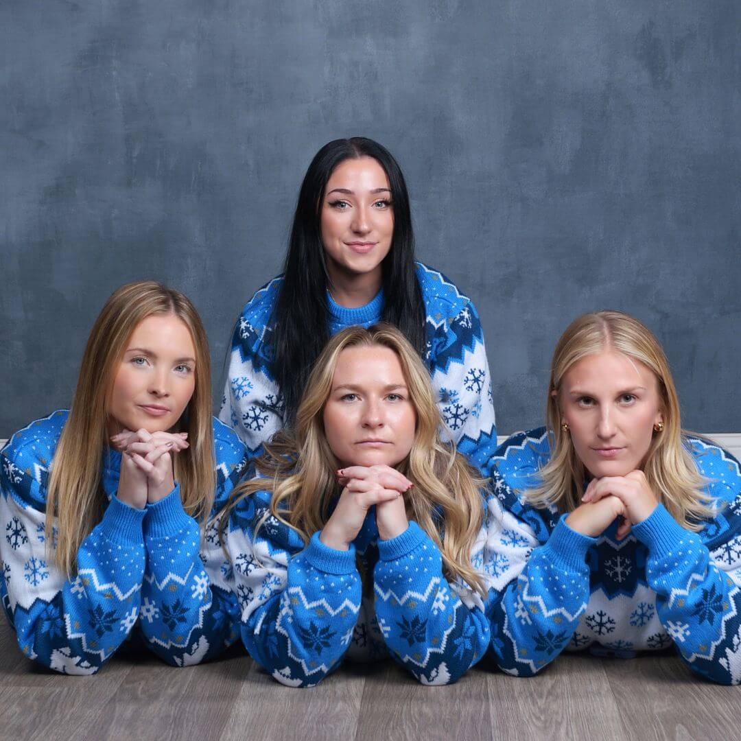 Four women in holiday sweaters posing for awkward holiday photos