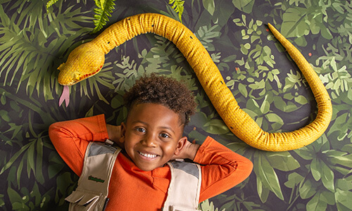 Boy posing with a snake prop for jungle photography at JCPenney Portraits.