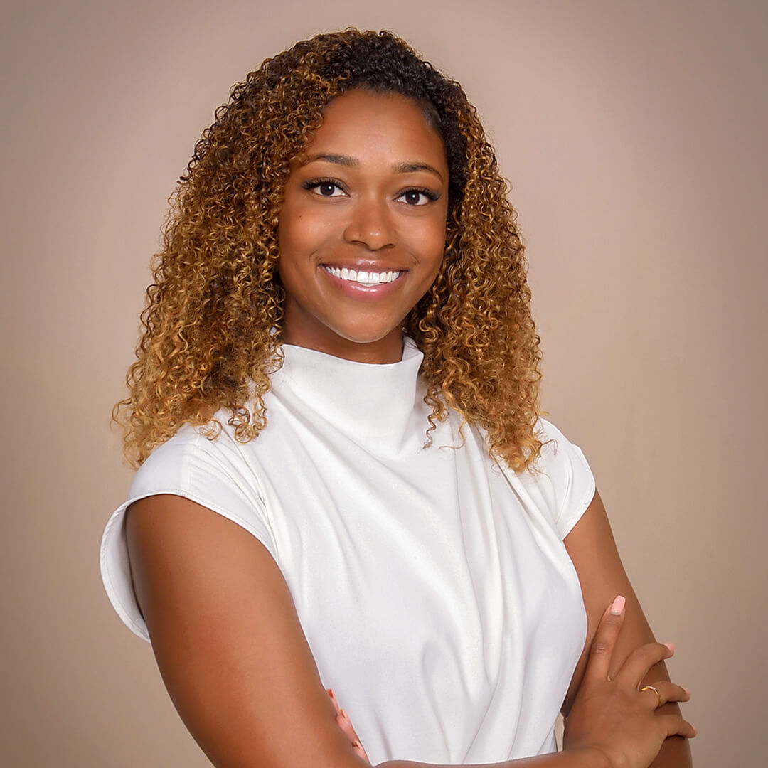 Woman in a white top posing for business headshots on the latte background.