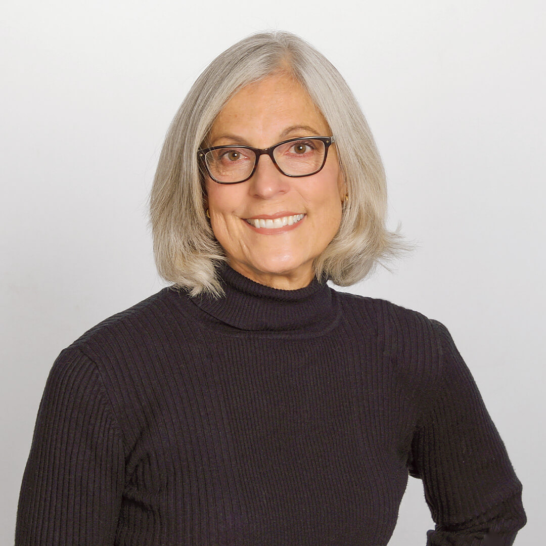 Woman in a black turtleneck posing for business headshots on a white background.
