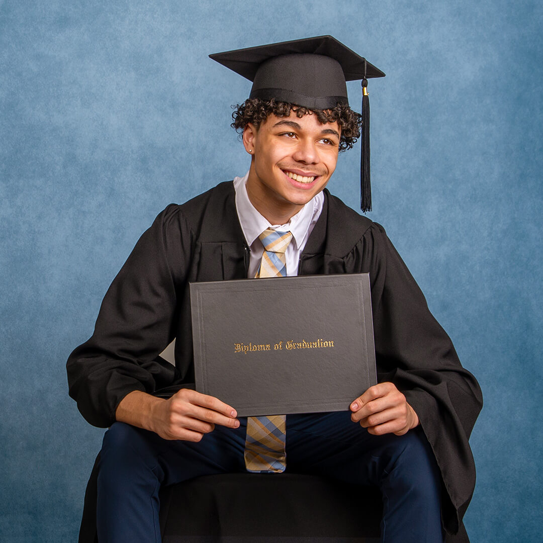 Man holding a diploma posing for graduation photos.