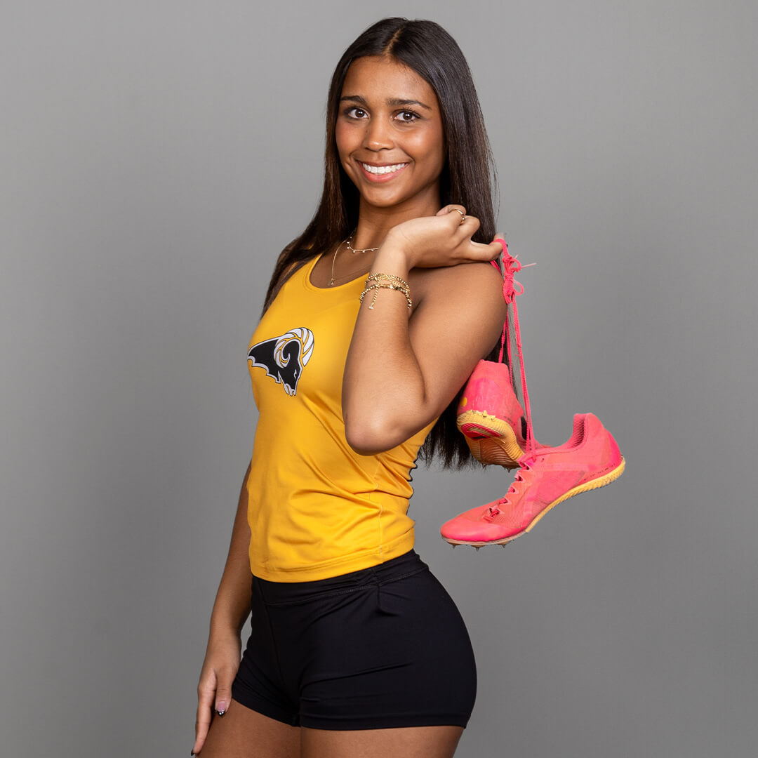 Woman posing for senior pictures wearing a high school track uniform.