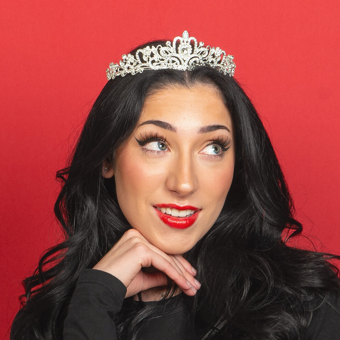 Woman wearing a crown posing for candid photos on a red background.